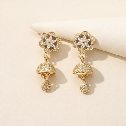Close-up of rose gold drop earrings featuring geometric studs and starburst crystal charm