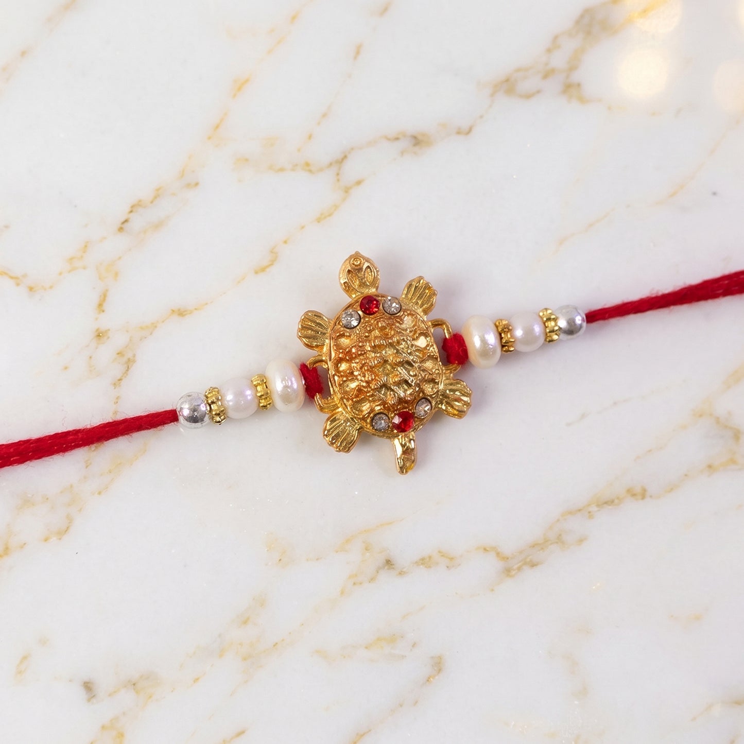 Gold Turtle Charm Rakhi with Pearl Sides and Red Mauli Thread