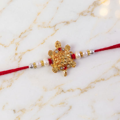 Gold Turtle Charm Rakhi with Pearl Sides and Red Mauli Thread