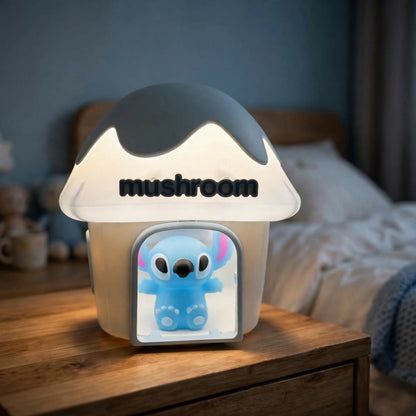A mushroom house night light with a dark gray cap, illuminating a blue Stitch character on a wooden bedside table.
