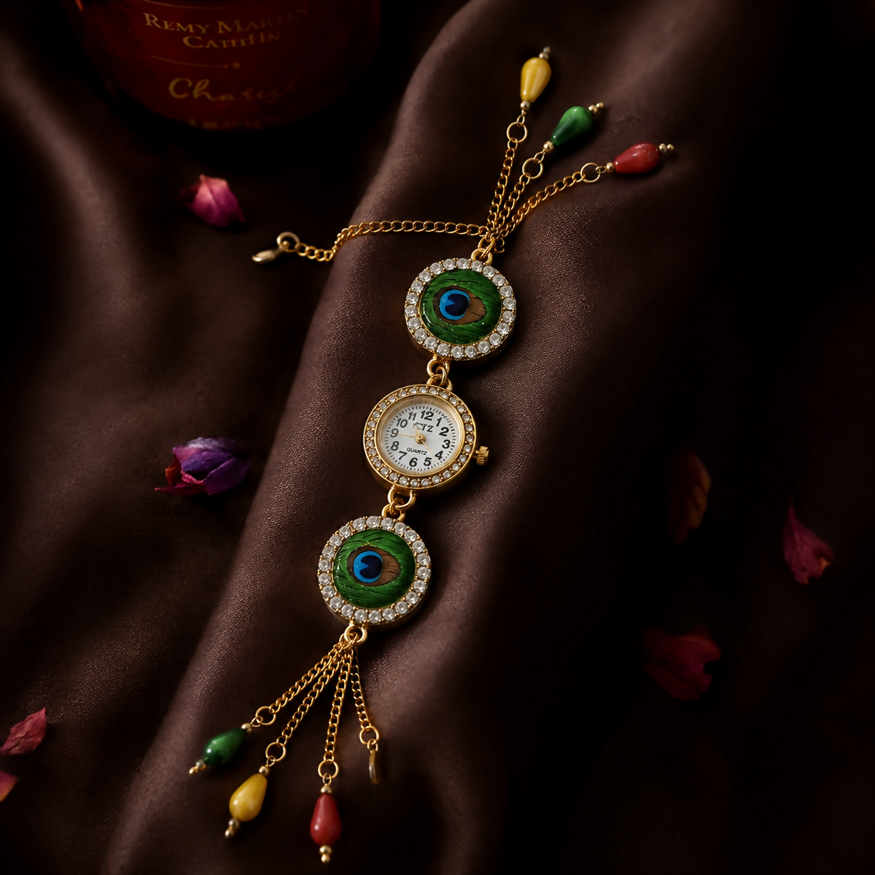 A gold-tone bracelet watch with peacock eye designs, a central watch face, and colorful beads is elegantly placed on a rich