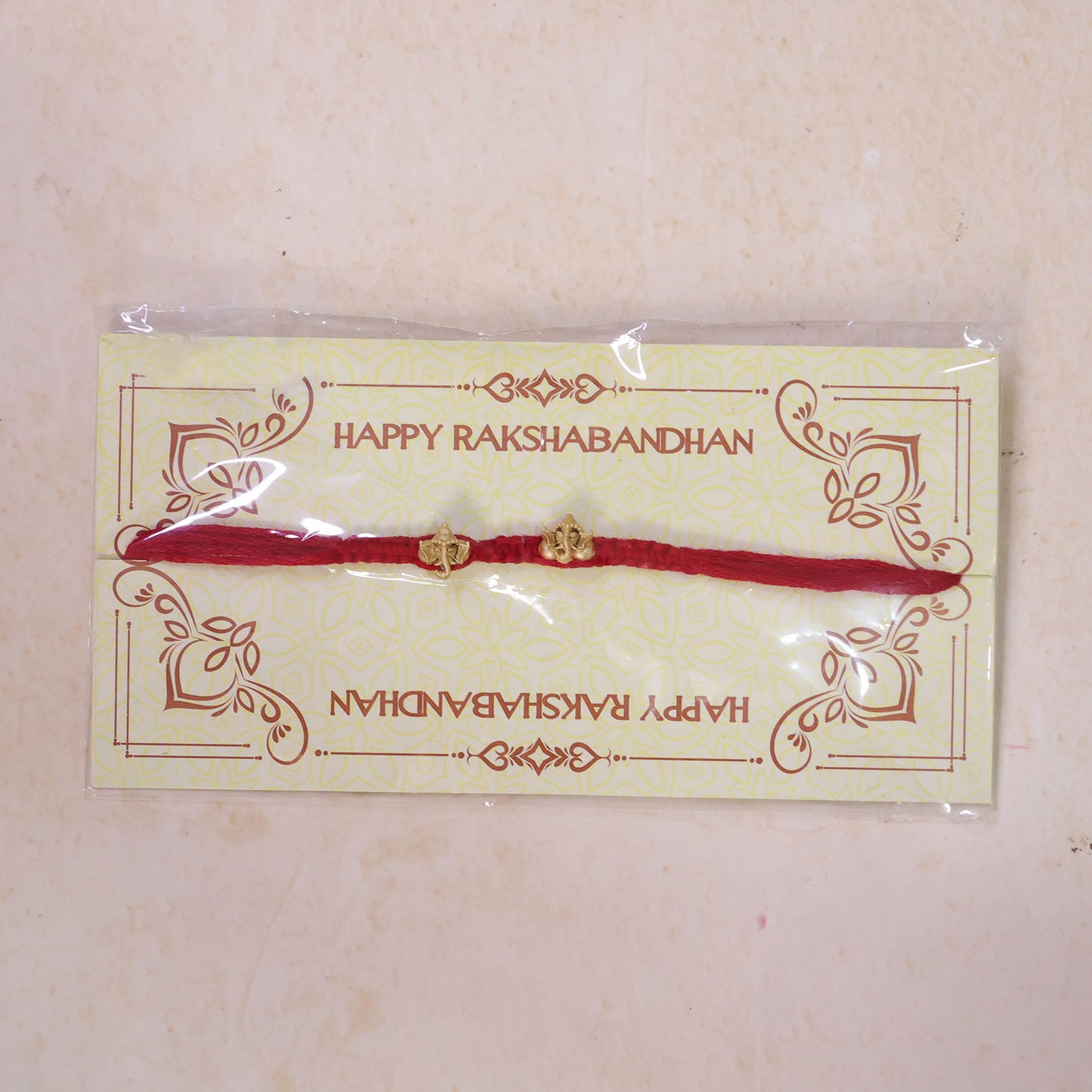 Red Thread Rakhi with Twin Antique Gold Ganesha Shaped Charms