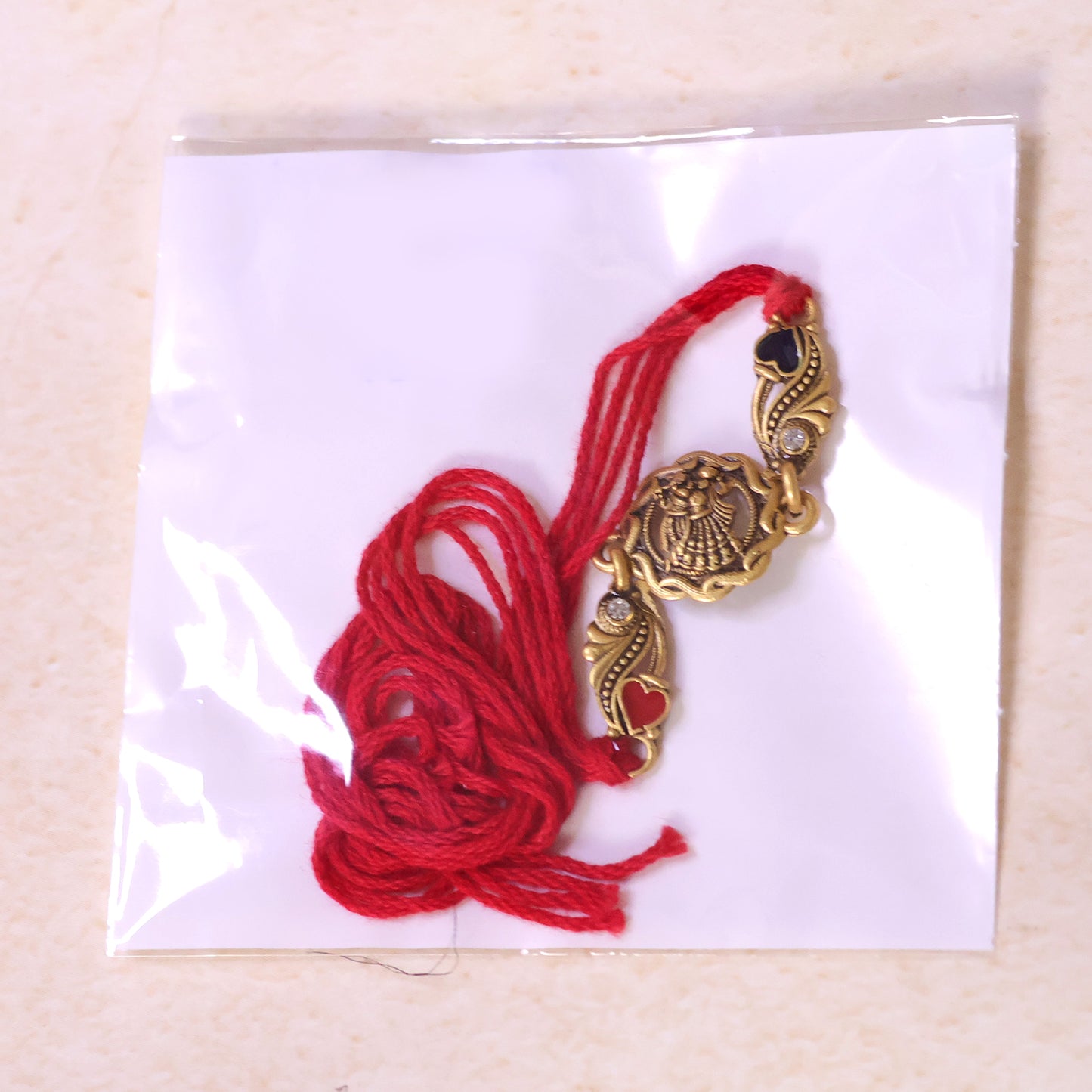 Antique Gold-Toned Radha Krishna Rakhi with Crystal Accents, Enamel Hearts & Red Thread
