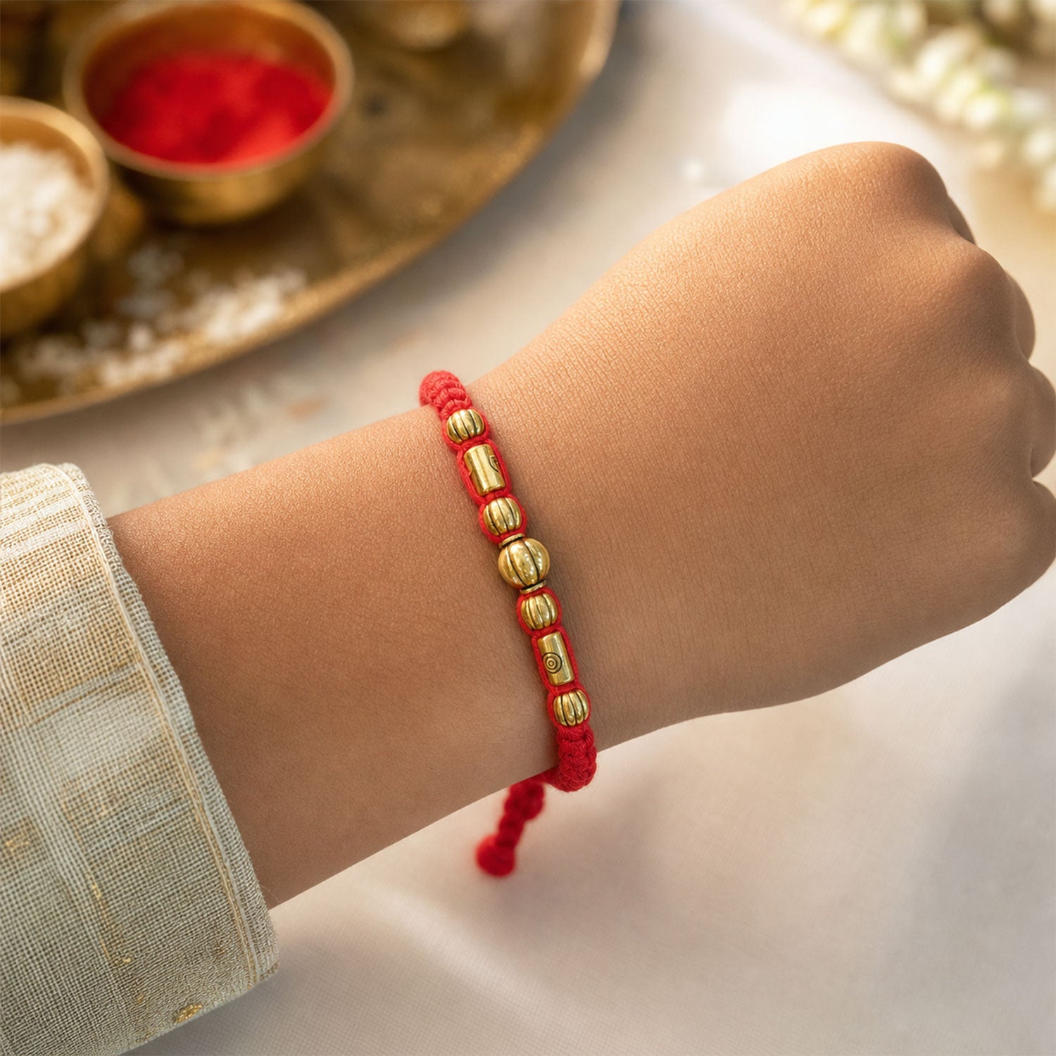 Red Braided Rakhi with a Row of Smooth Golden Bead Accents