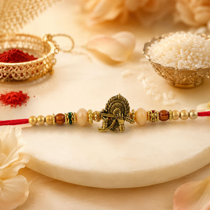 Krishna Flute Peacock Devotional Rakhi with Antique Gold Centre and Peach Beads