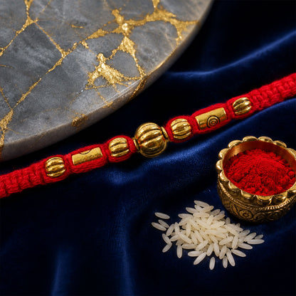 Red Braided Rakhi with a Row of Smooth Golden Bead Accents
