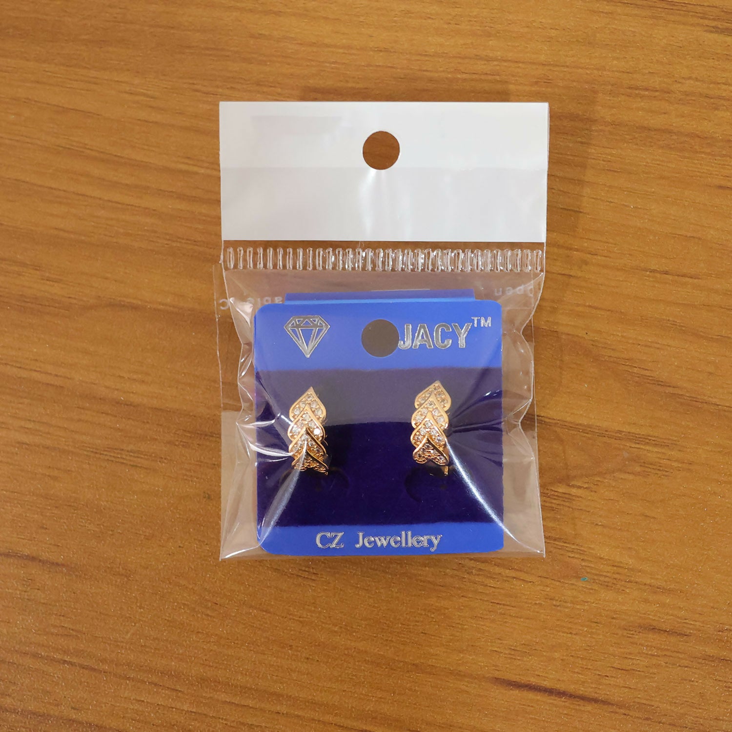 Close shot of gold leaf pattern stud earrings with glittering stone accents
