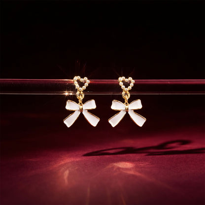 Elegant gold-trimmed pearl earrings with heart and bow design