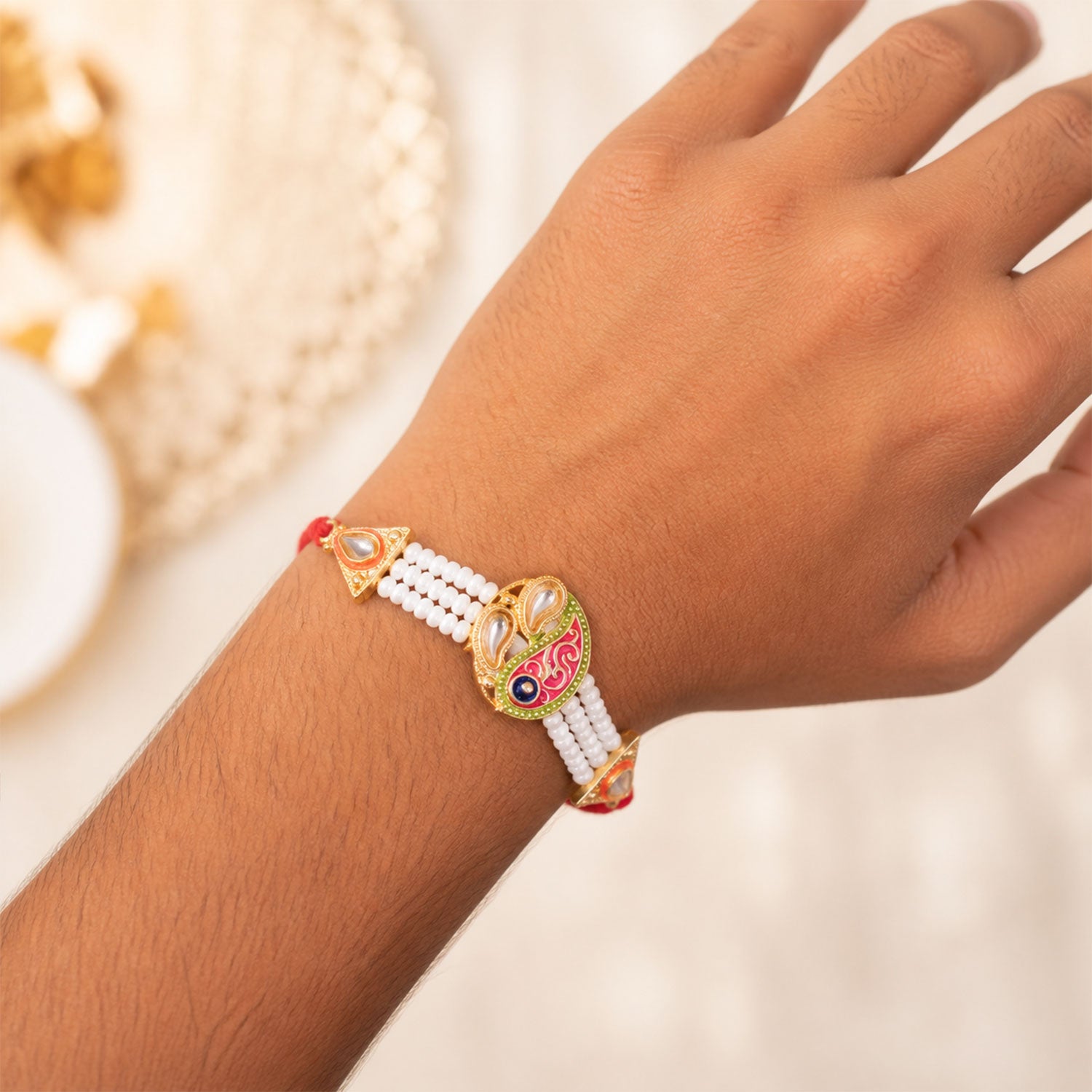 Pearl Paisley Rakhi with Red Thread and Golden Festive Brother Gift Presentation