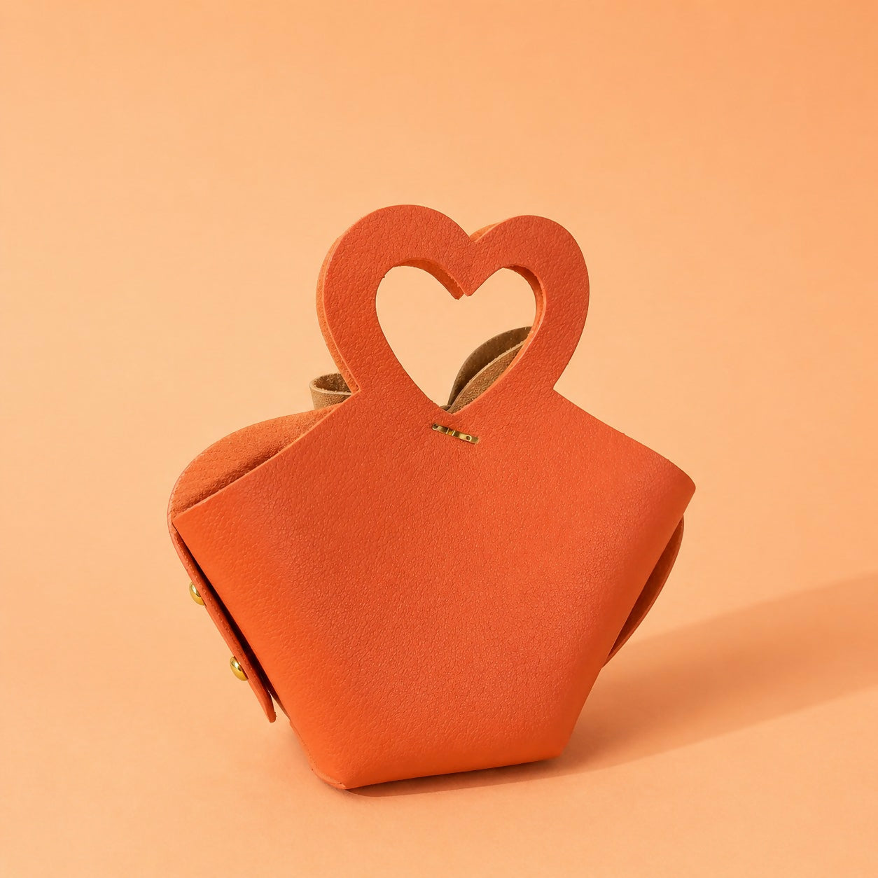 Orange handbag with heart handle and bow detail side view