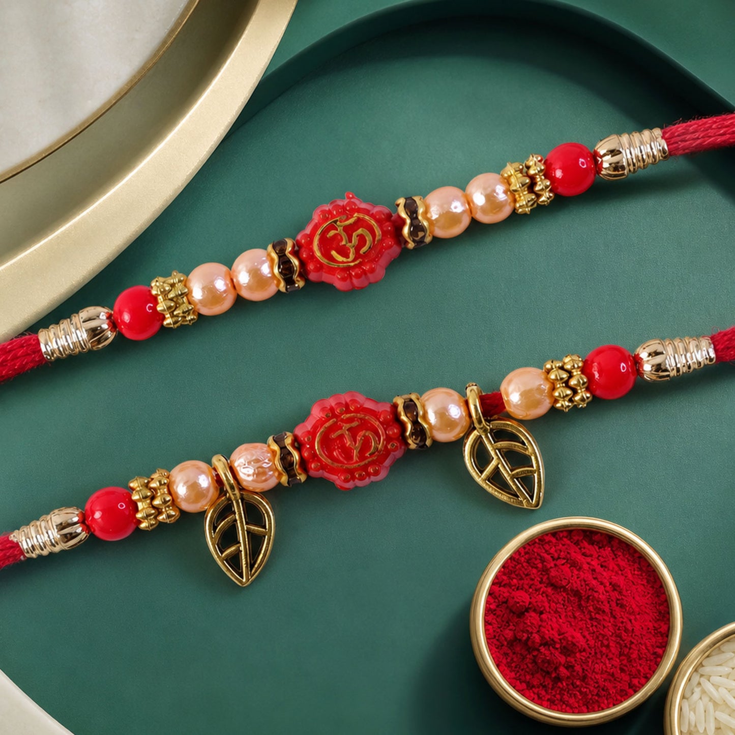 Couple Om Rakhi Set with Red Beads, Golden Leaf Charms and Festive Lumba Pair Design
