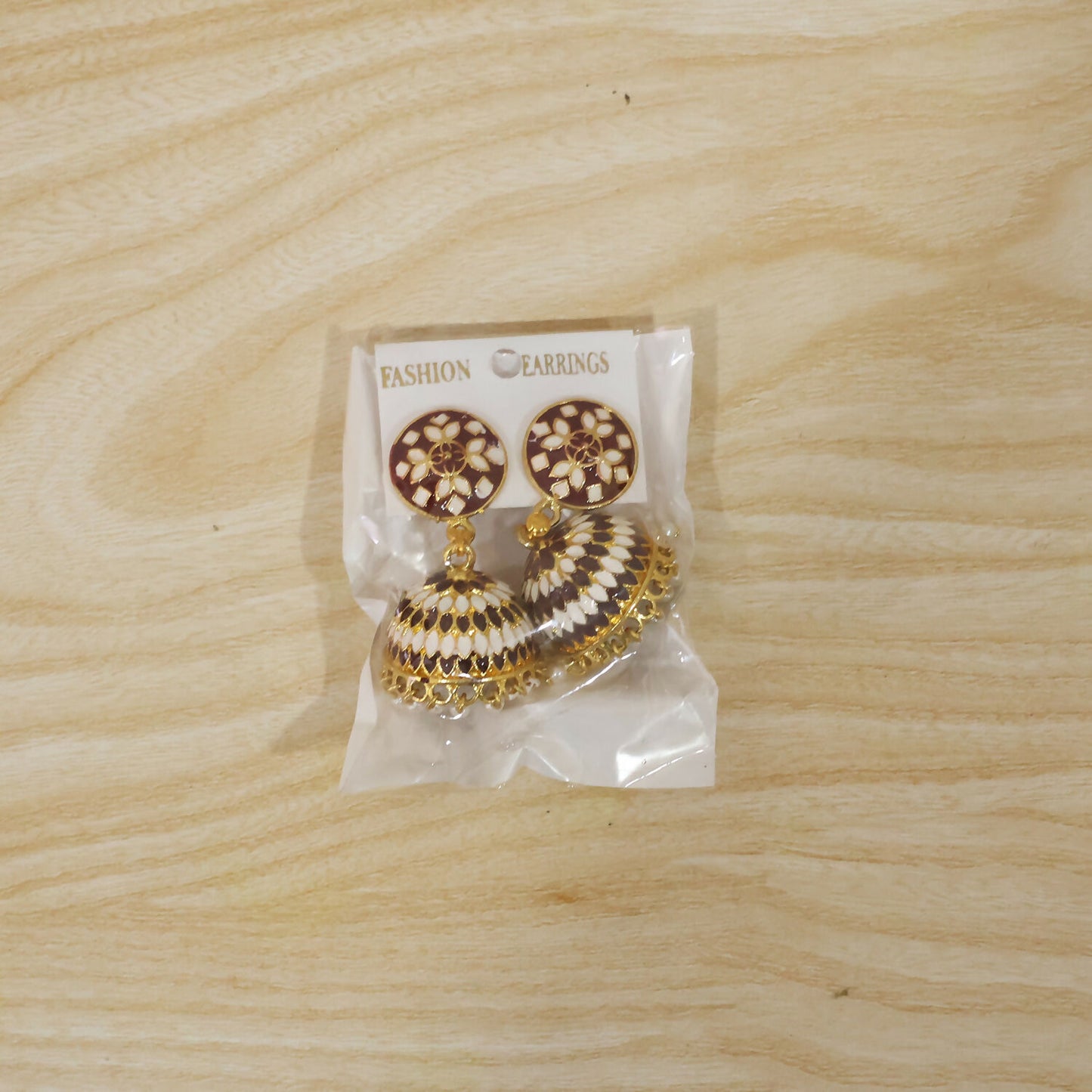 Maroon jhumka earrings with pearl beads worn on ear