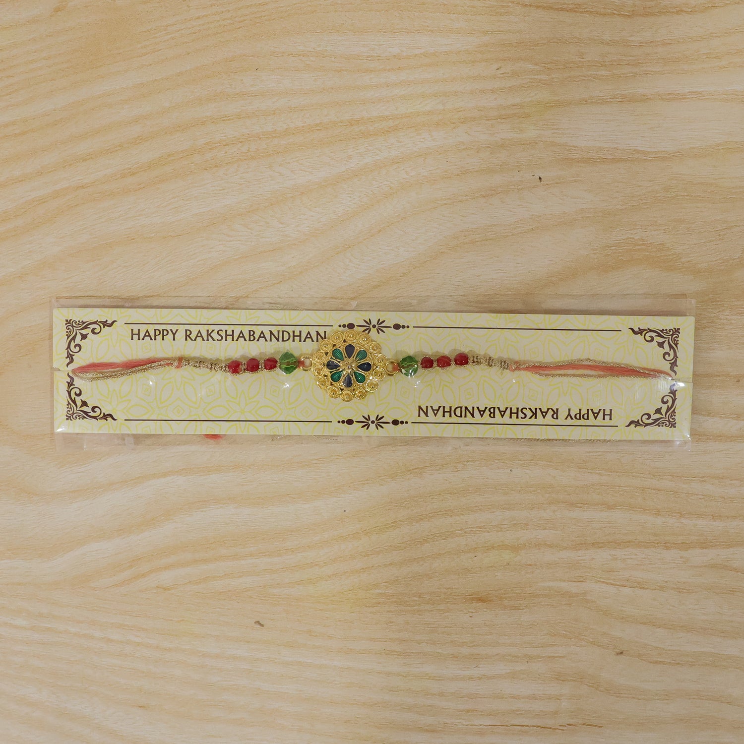 Gold Blue Flower Rakhi with Green Beads and Red Pearl Accents