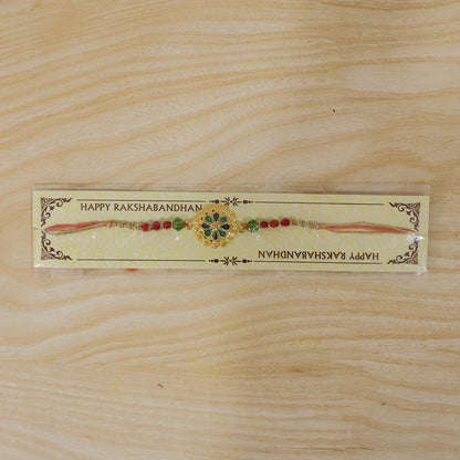 Gold Blue Flower Rakhi with Green Beads and Red Pearl Accents
