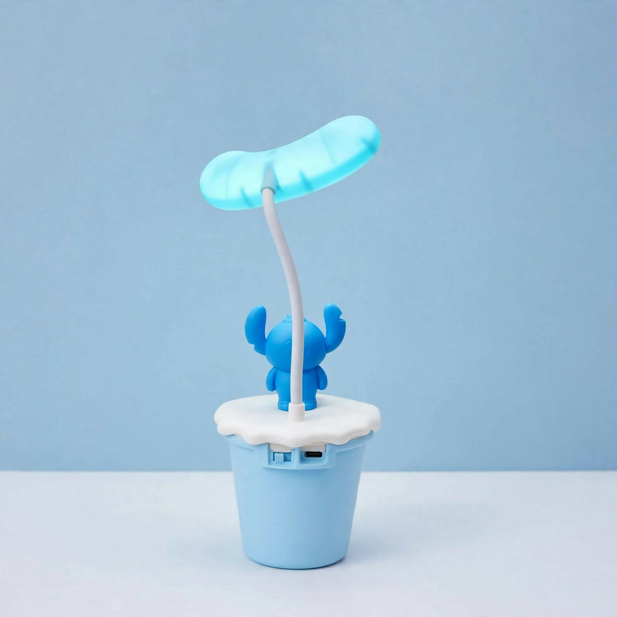 The back of the blue Stitch desk lamp, showing the USB charging port on the light blue base.