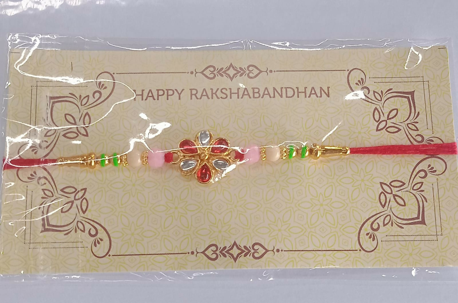 Artistic shot of elegant red and white rakhi with floral kundan centerpiece