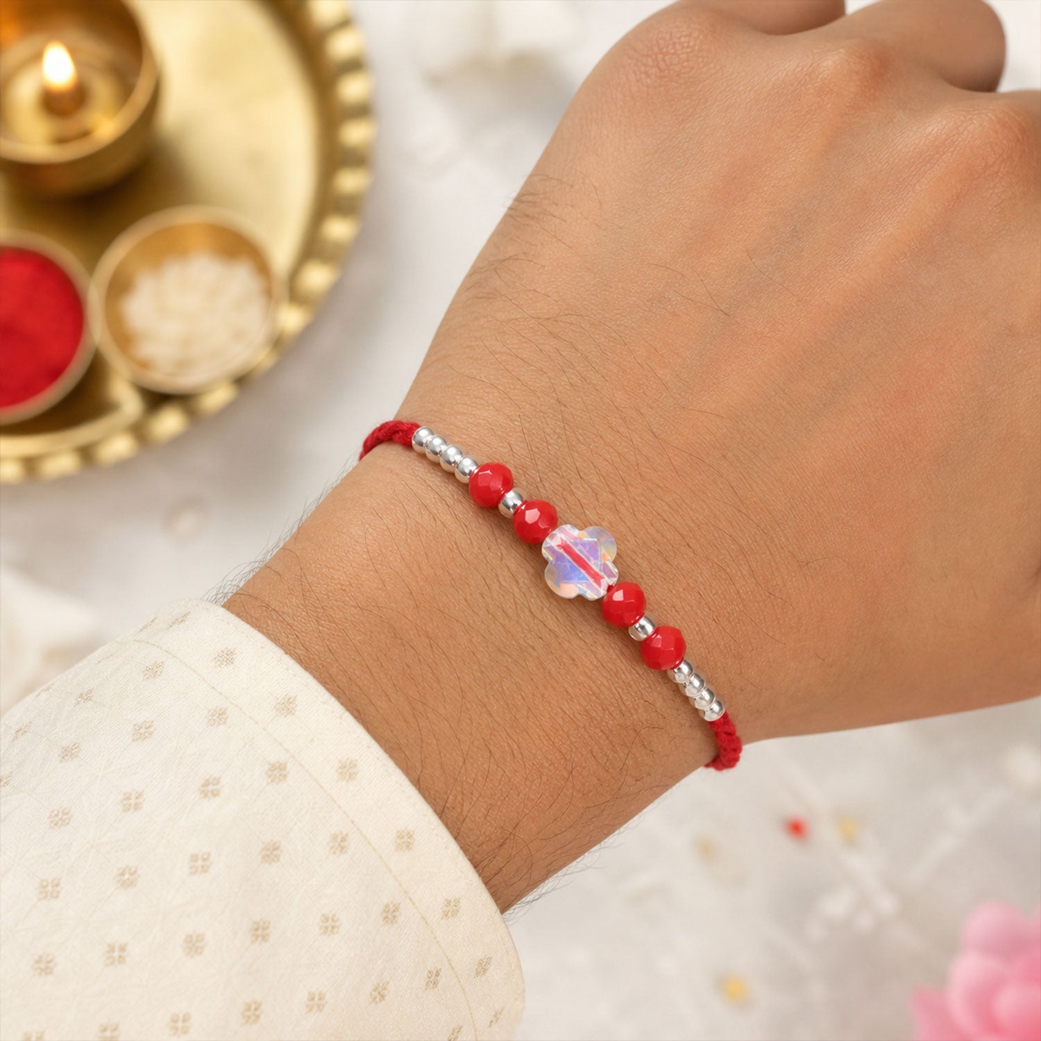 Red Thread Rakhi with Red Beads and an Iridescent Quatrefoil Crystal