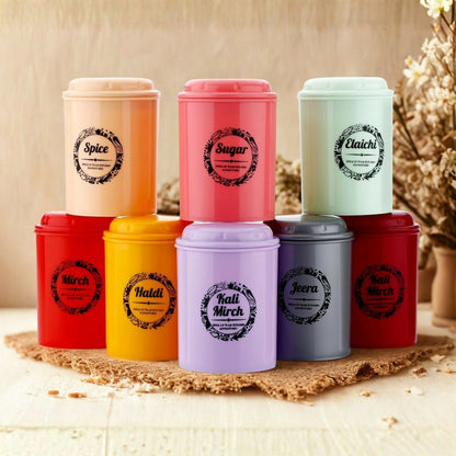 A combo of eight colorful airtight spice containers on a woven mat, with a blurred background of dried flowers.