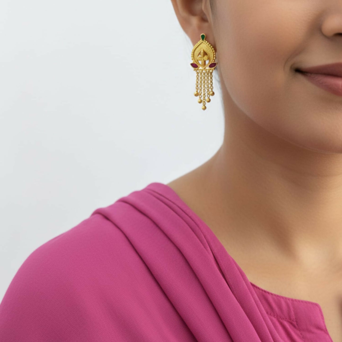 Close-up of traditional gold-plated jhumka earrings with bell-shaped drop and golden beads
