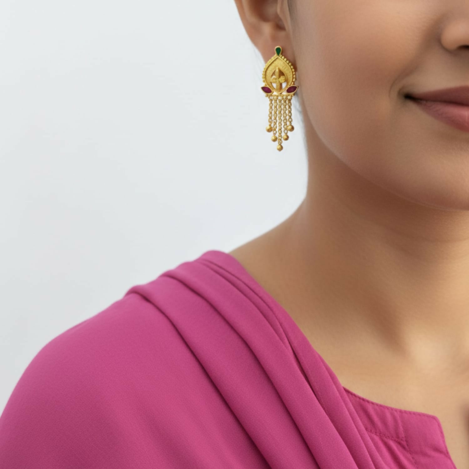 Close-up of traditional gold-plated jhumka earrings with bell-shaped drop and golden beads