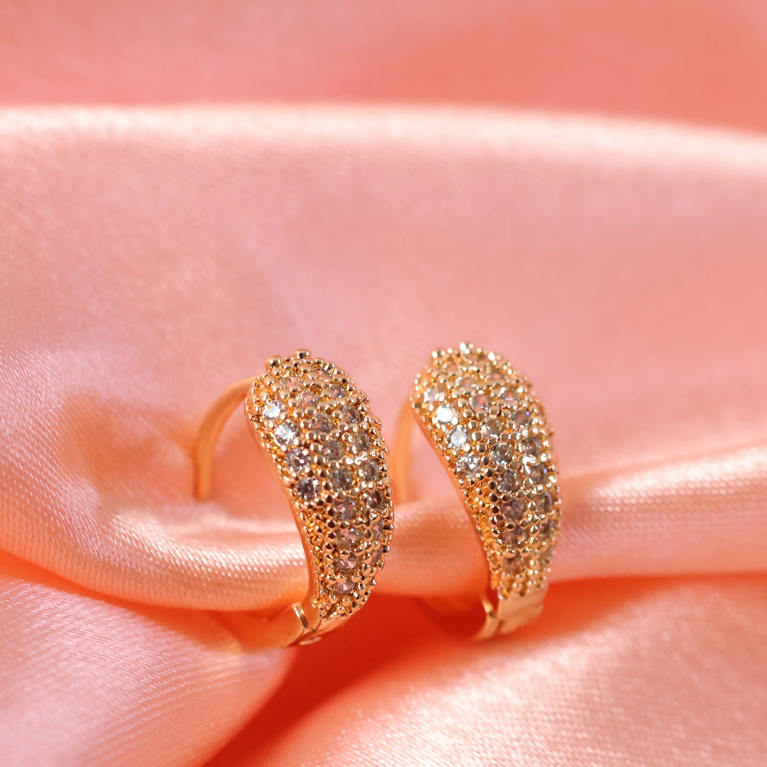 Pair of gold crystal huggie hoop earrings with smooth polished interior for comfort