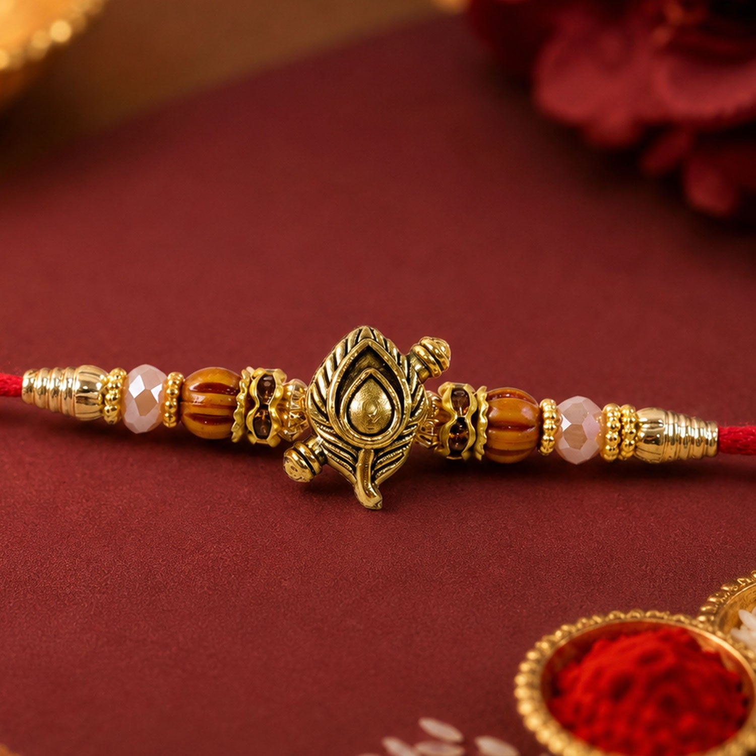 Peacock Paisley Golden Rakhi with Leaf Style Centre, Red Thread and Pearl Accents