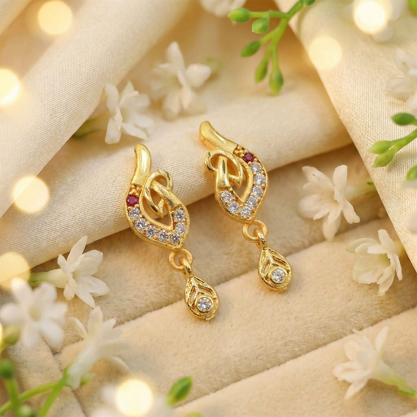 Gold leaf drop earrings with white and red stones on white background