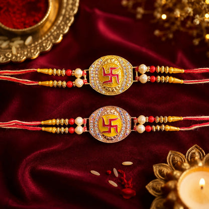 Two gold and rose gold Swastik bracelets with red and yellow threads are displayed on a rich red velvet cloth with scattered