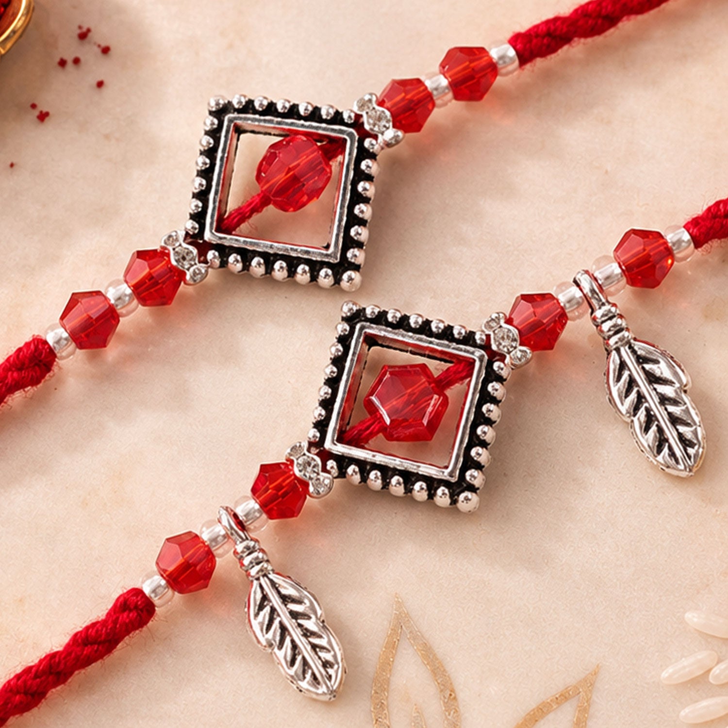 Red Gem Square Rakhi Set with Silver Bead Border and Leaf Charms for Couple Gift