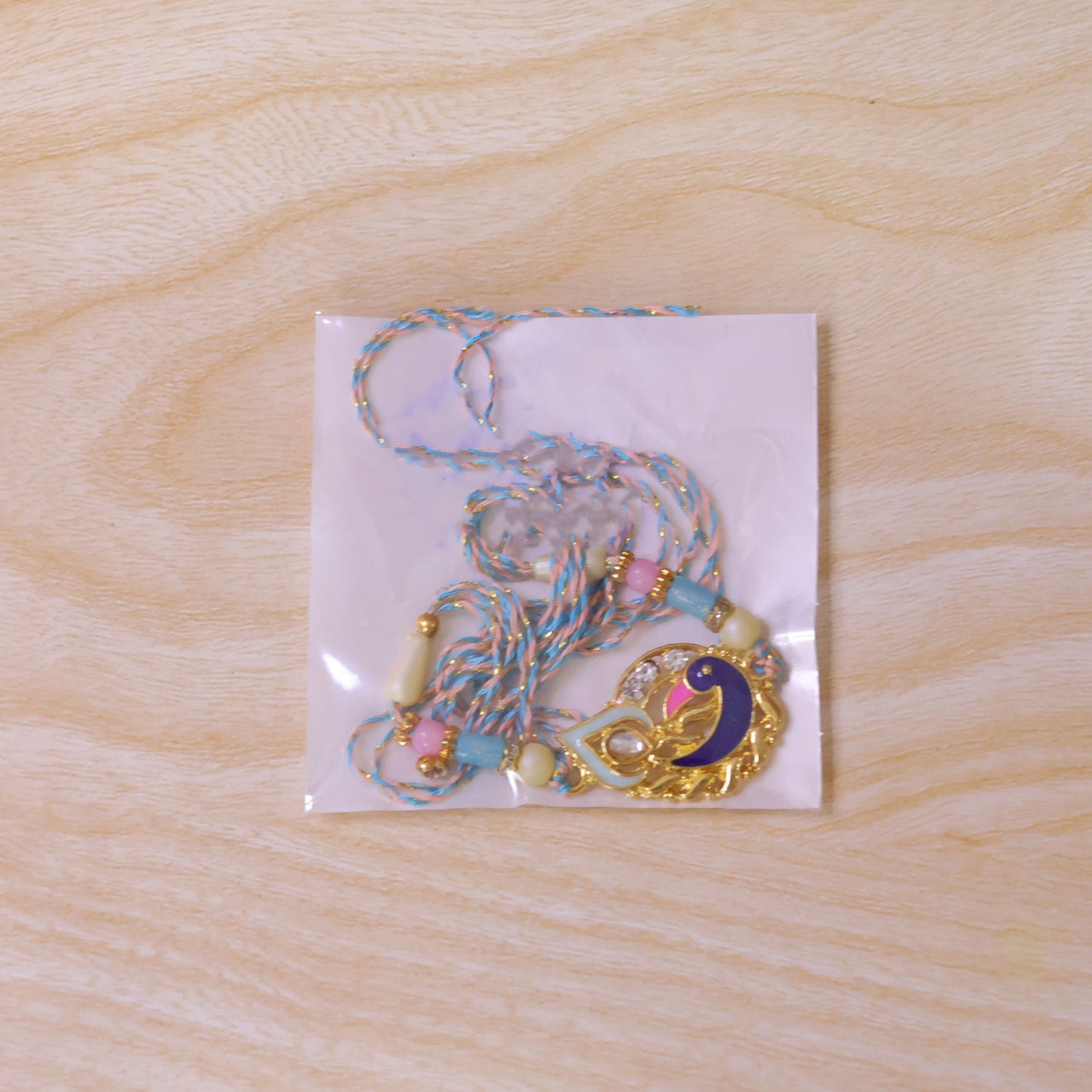 Festive Rakhi featuring Peacock Charm, blue stones and wrist style for Raksha Bandhan