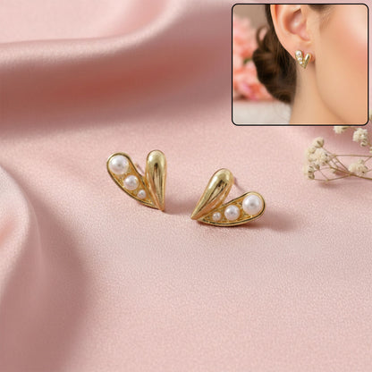 Gold heart stud earrings with pearl detail on white background