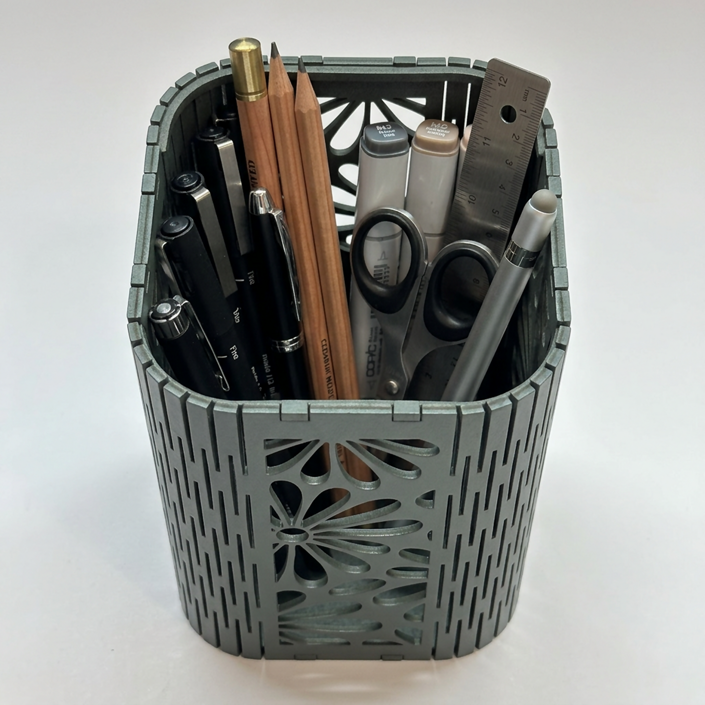 The Floral Mesh Pen Holder positioned on an office desk next to a laptop.