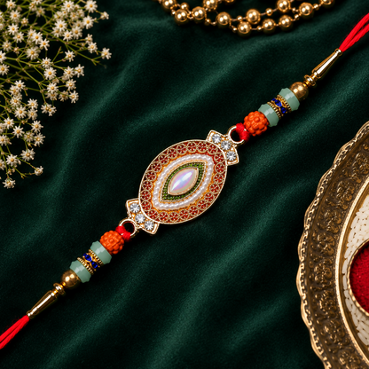 An ornate Rakhi features a central oval with a white stone, surrounded by red, gold, and green beads on a dark green velvet