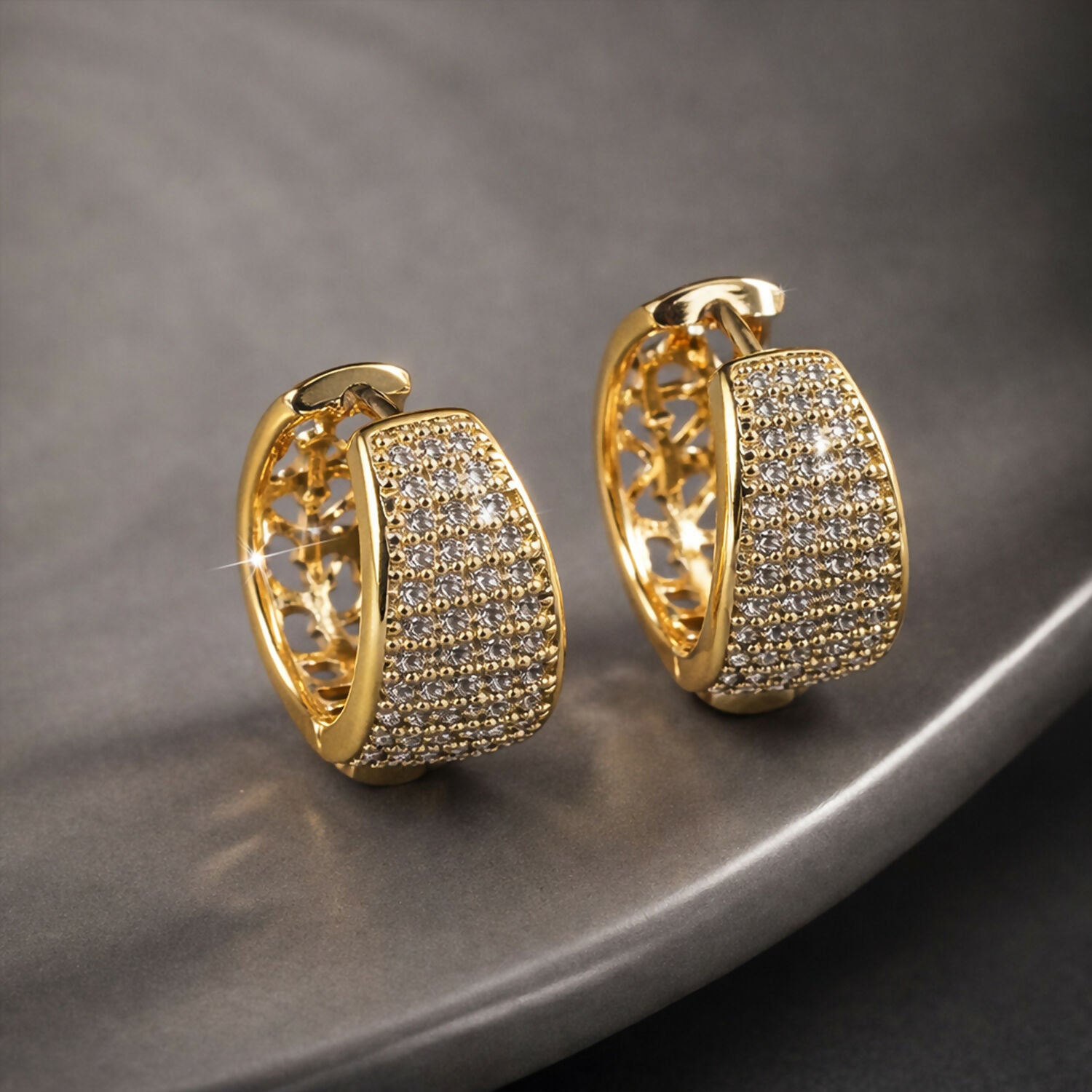 Wide huggie style gold hoop earrings with rows of shimmering crystals