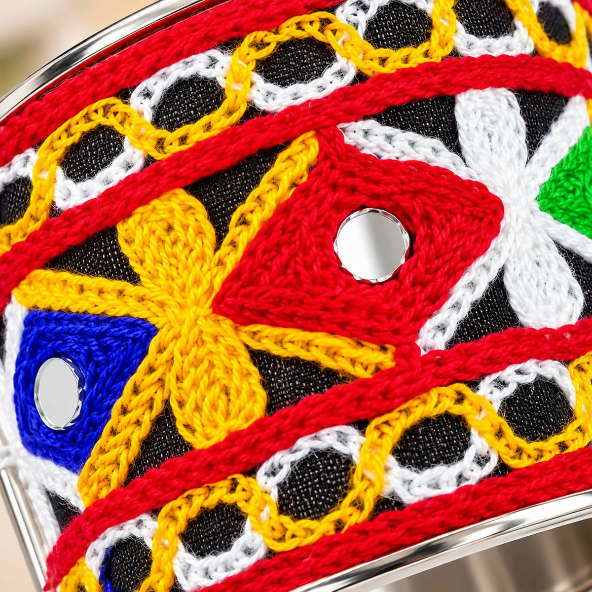 Close-up of the bracelet showing red, yellow, blue, and white thread embroidery with small round mirrors.
