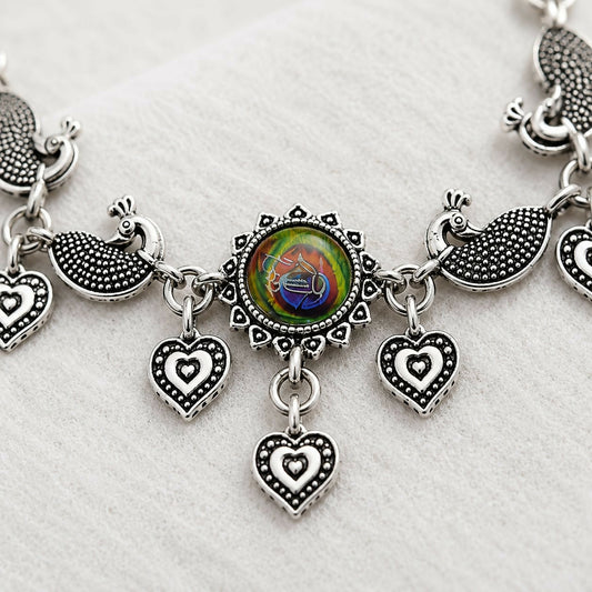 Close-up of an oxidized silver bracelet with a central colorful peacock feather design, flanked by two peacock motifs and
