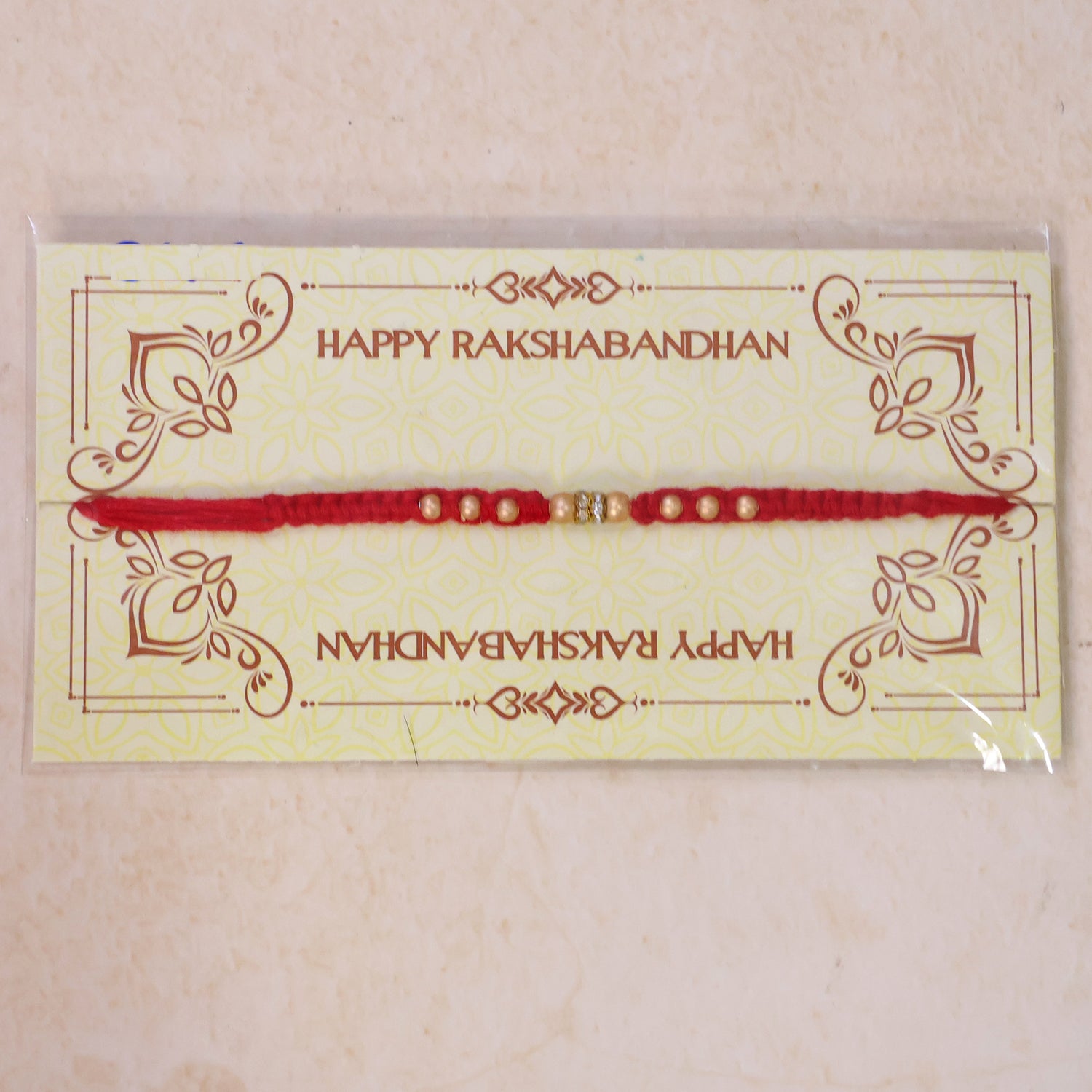 Red Thread Rakhi with Smooth Golden Beads and Sparkling Rhinestone Spacer