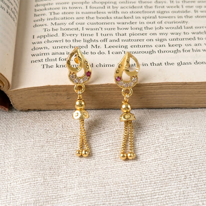 Detailed shot of traditional gold earrings featuring intricate leaf design and beads
