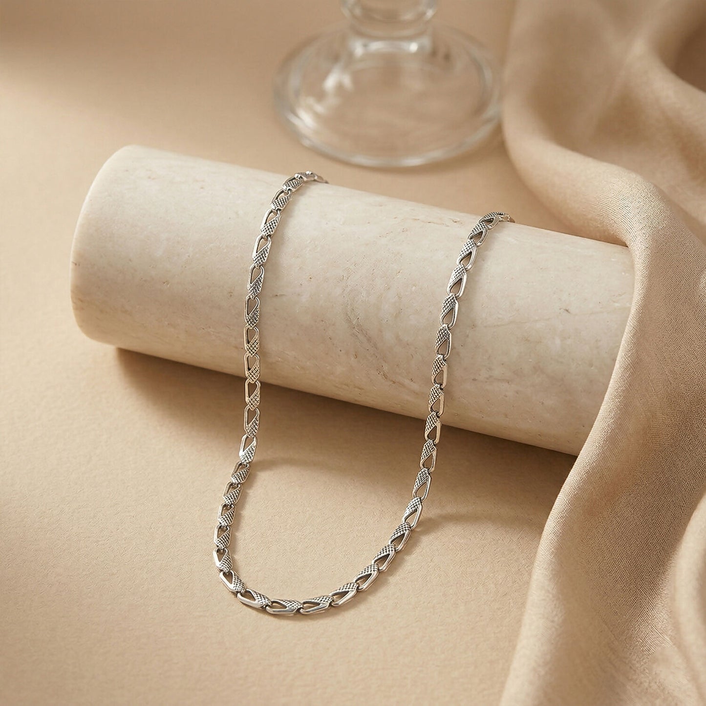 Close-up of silver textured chain necklace showing polished links