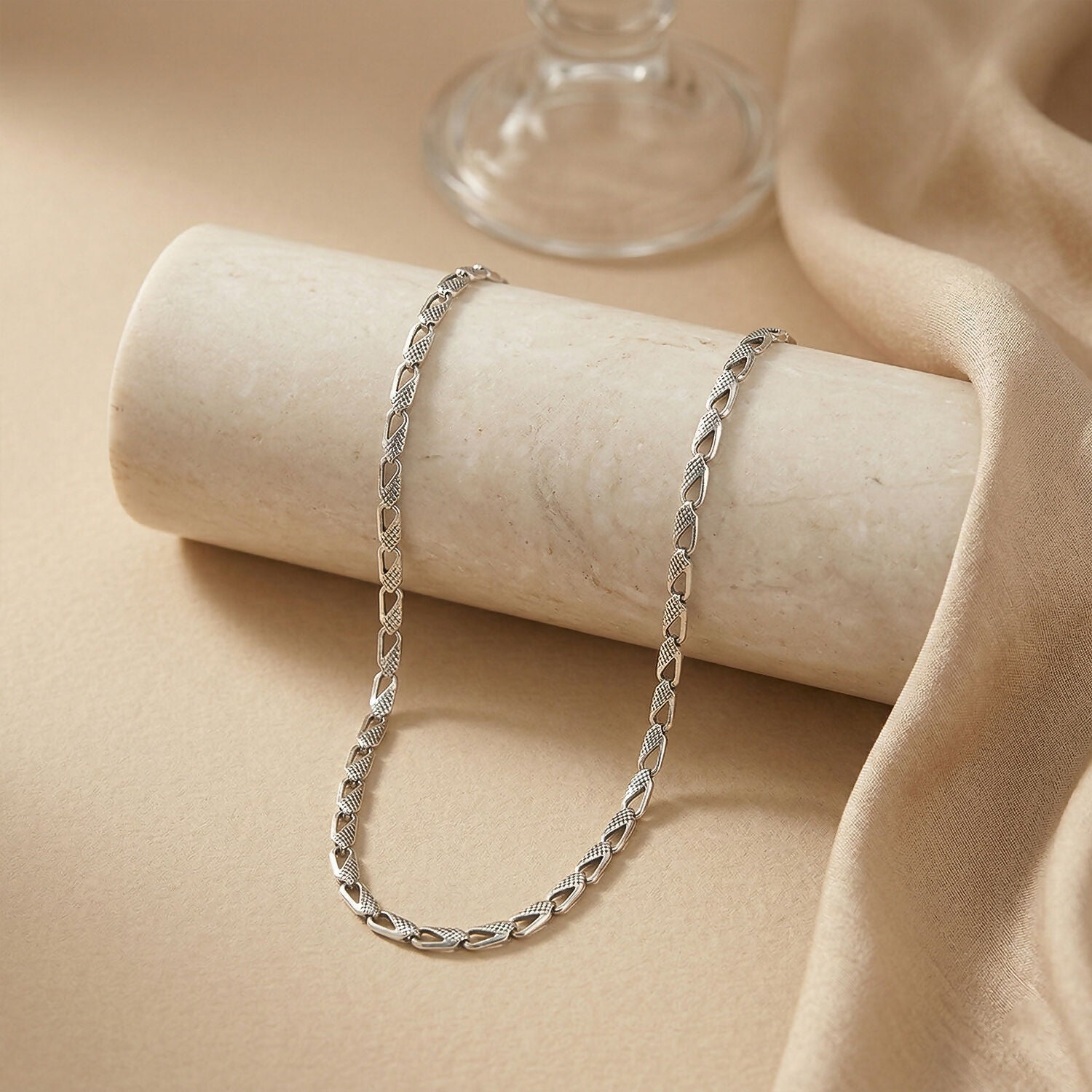 Close-up of silver textured chain necklace showing polished links