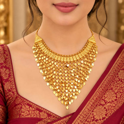 A woman models a striking gold bib necklace featuring a wide band and cascading leaf-like elements, paired with a red sari.