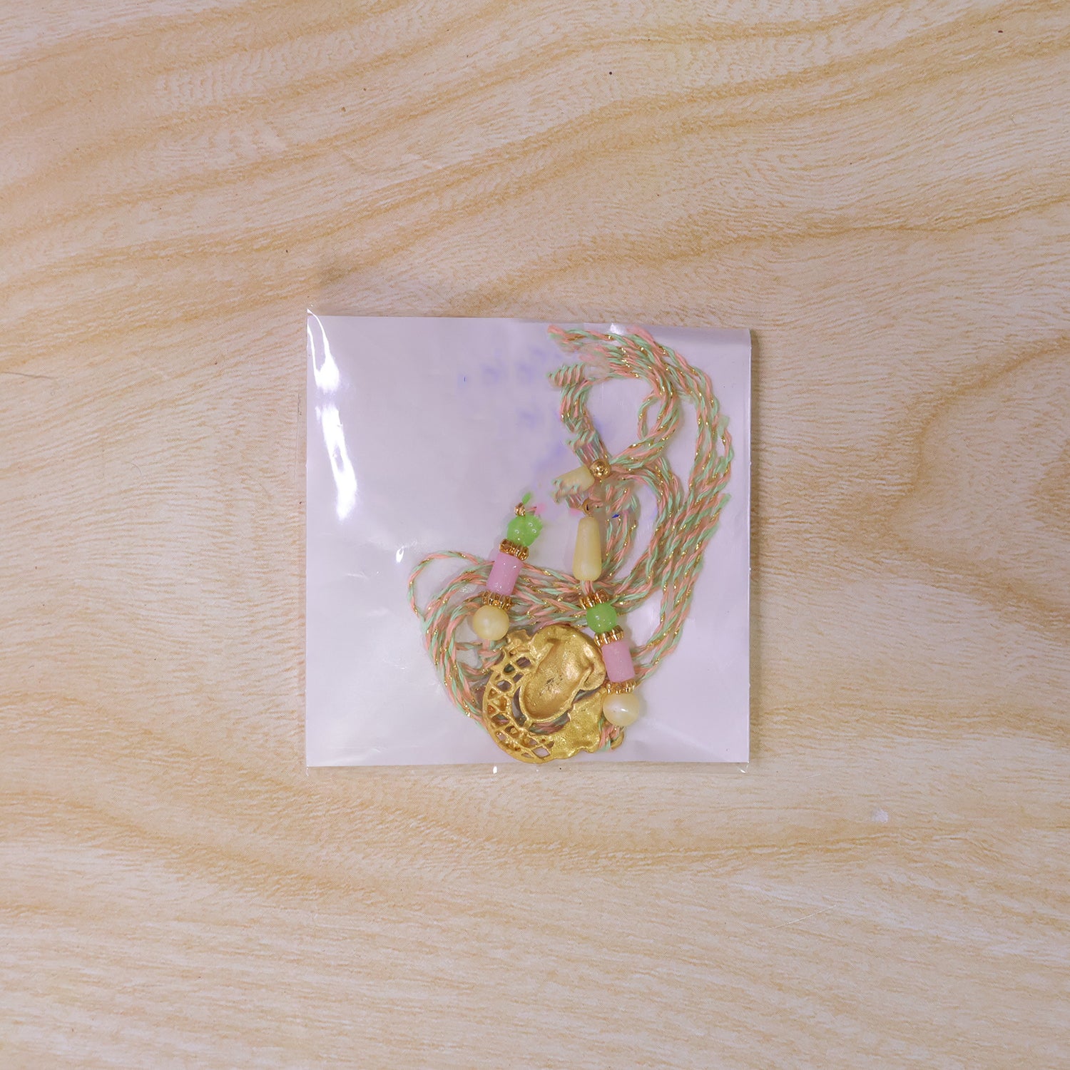 Textured Gold Om Pendant Rakhi with Leaf Accent and Pearl Beads