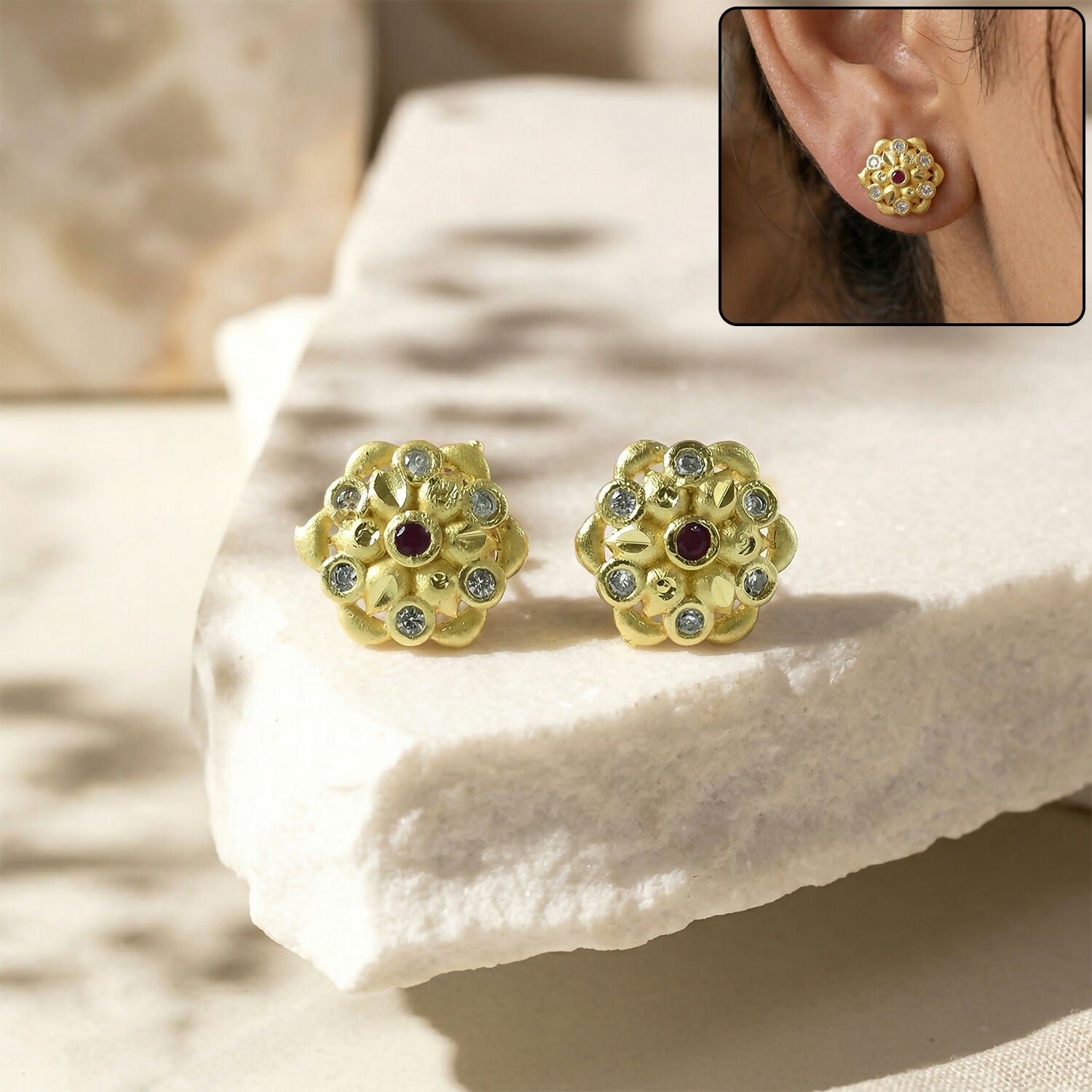 Close-up of modern circular gold stud earrings with crystal triangle design