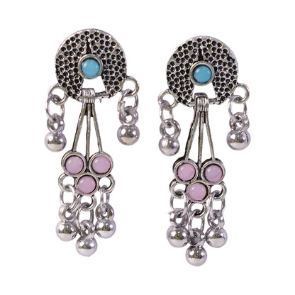 The oxidised silver long drop earrings with pink and turquoise stones and ghungroo bells are isolated on a white background.