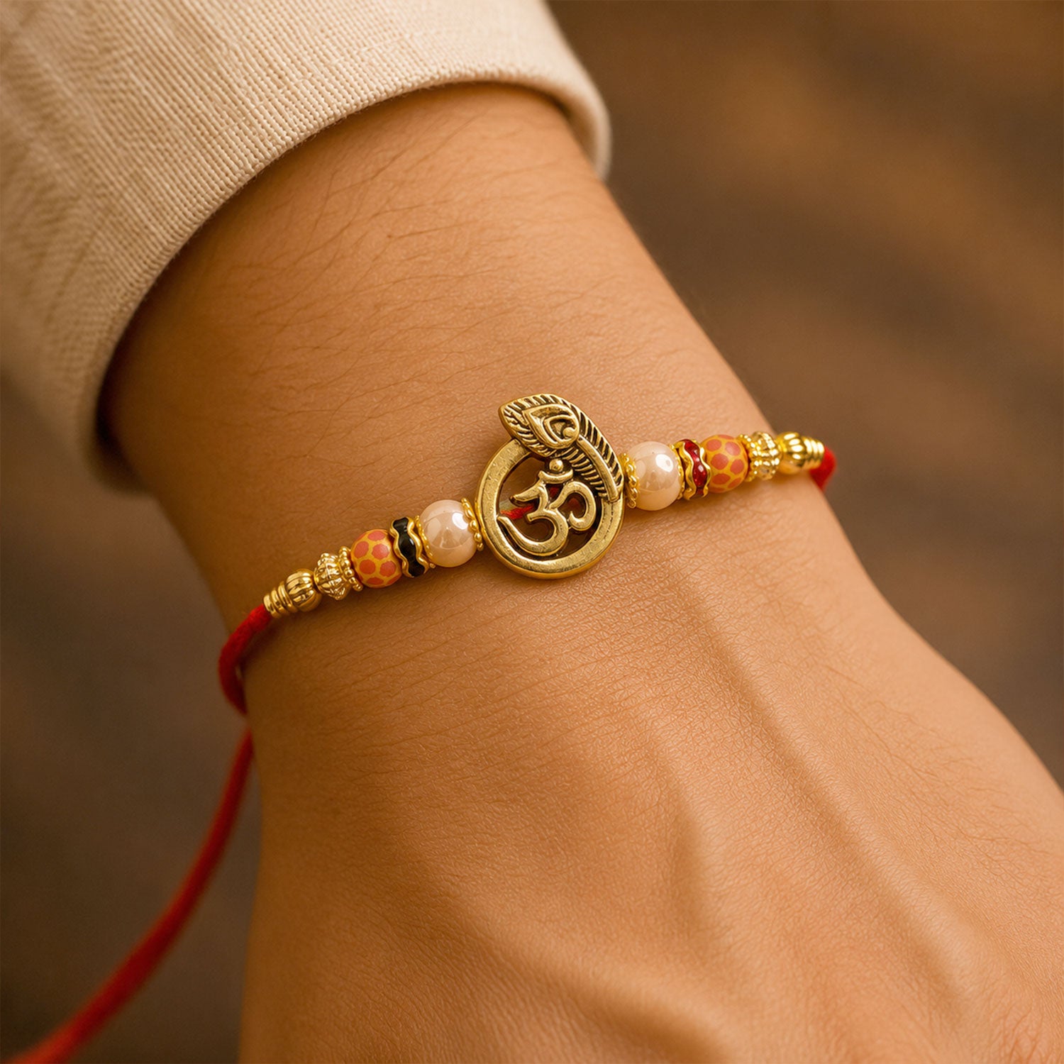 Om Peacock Golden Devotional Rakhi with Sacred Symbol, Pearl Beads and Red Thread