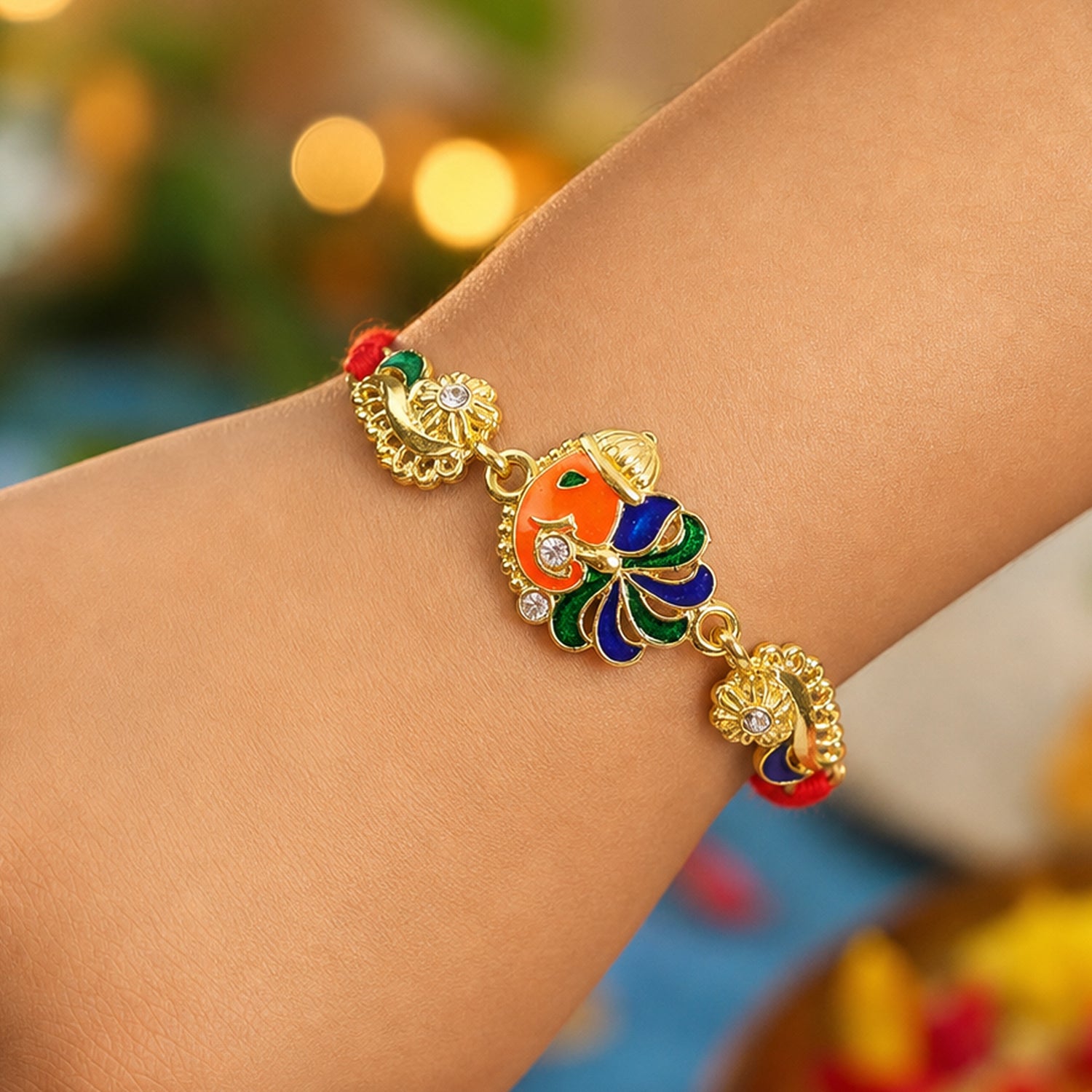 Gold-Toned Lord Ganesha Rakhi with Peacock Feather Enamel, Crystal Accents & Designer Red Thread