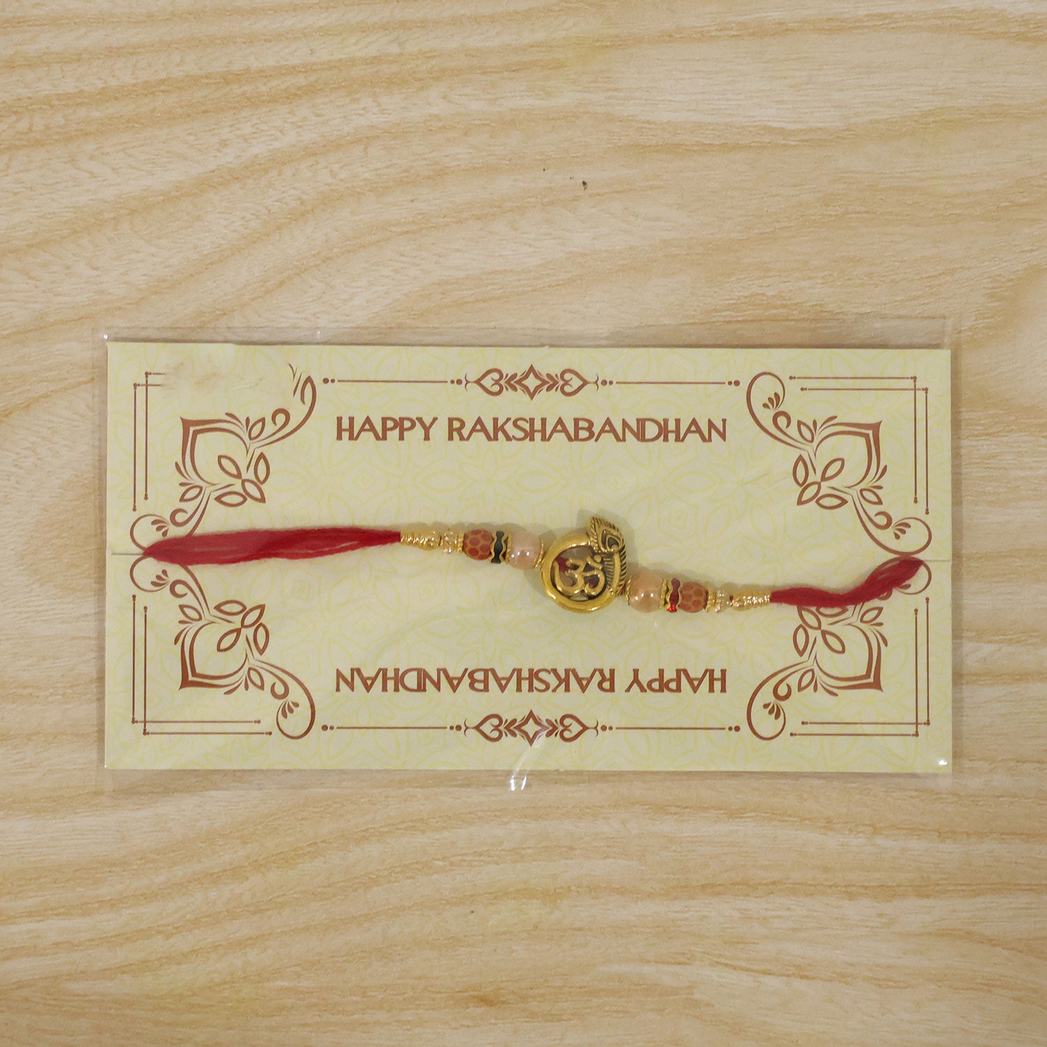 Om Peacock Golden Devotional Rakhi with Sacred Symbol, Pearl Beads and Red Thread