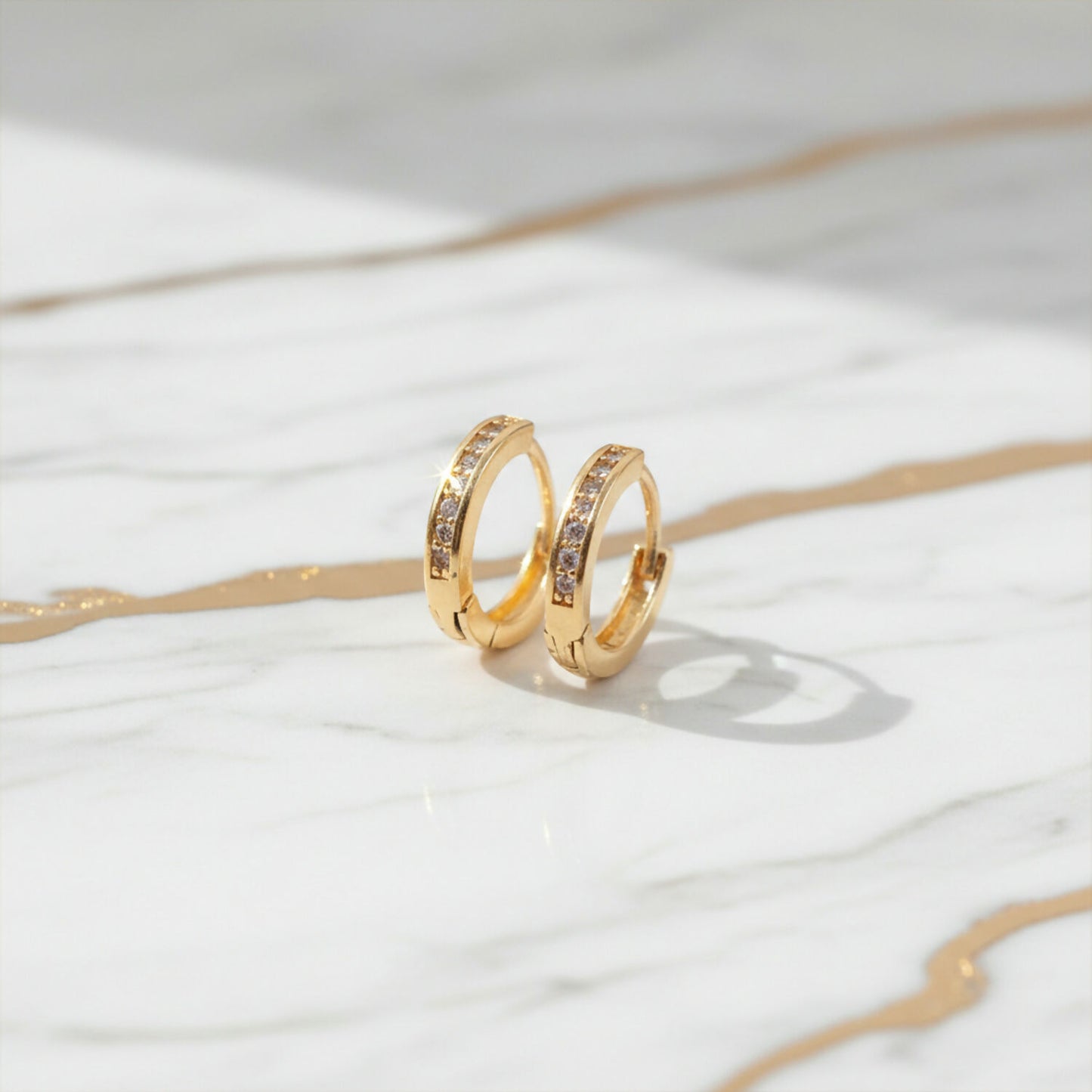 Gold finish crystal studded hoop earrings displayed to show classic circular design