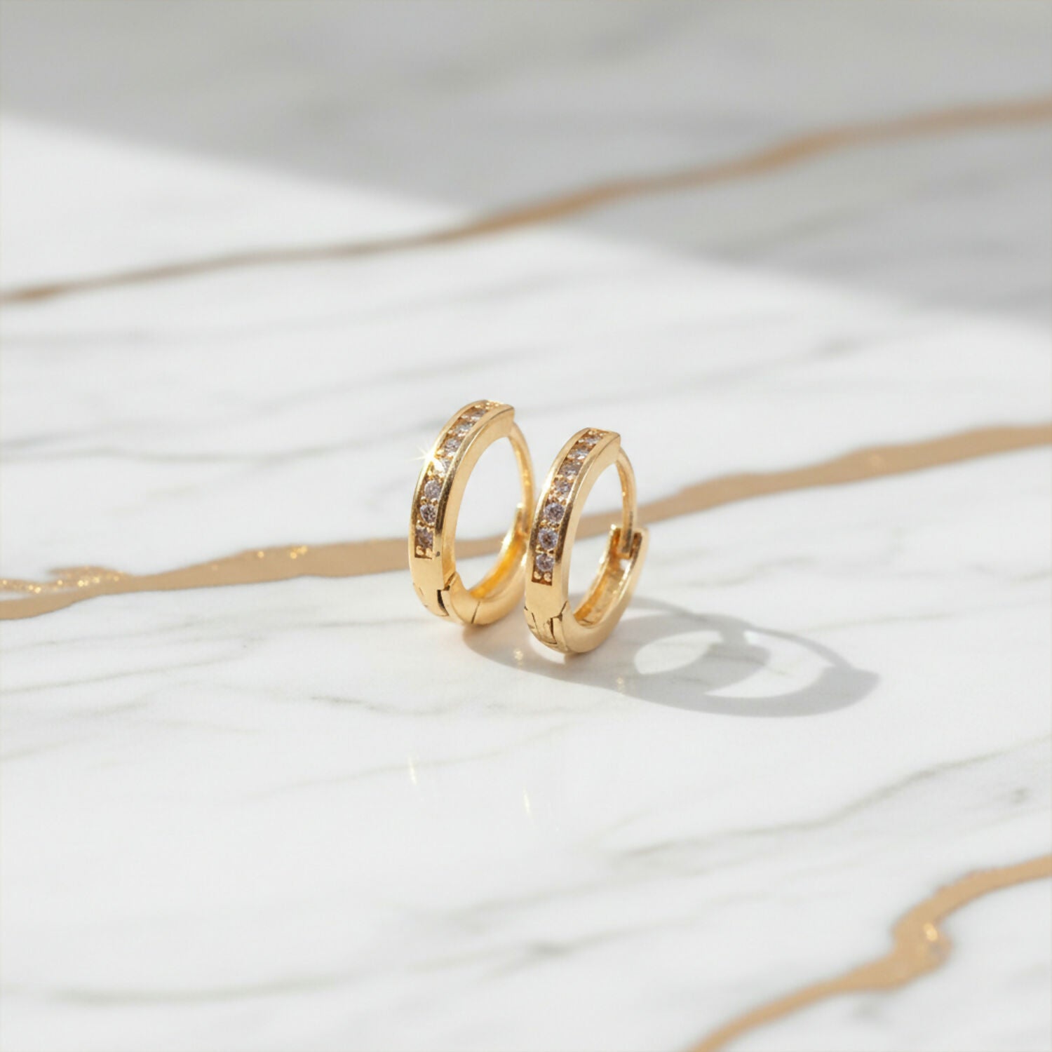 Gold finish crystal studded hoop earrings displayed to show classic circular design