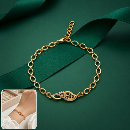 A gold-toned bracelet with a sparkling crystal-studded leaf charm on a dark green satin ribbon.